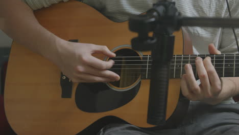 close up of fingers picking at a guitar in a recording studio