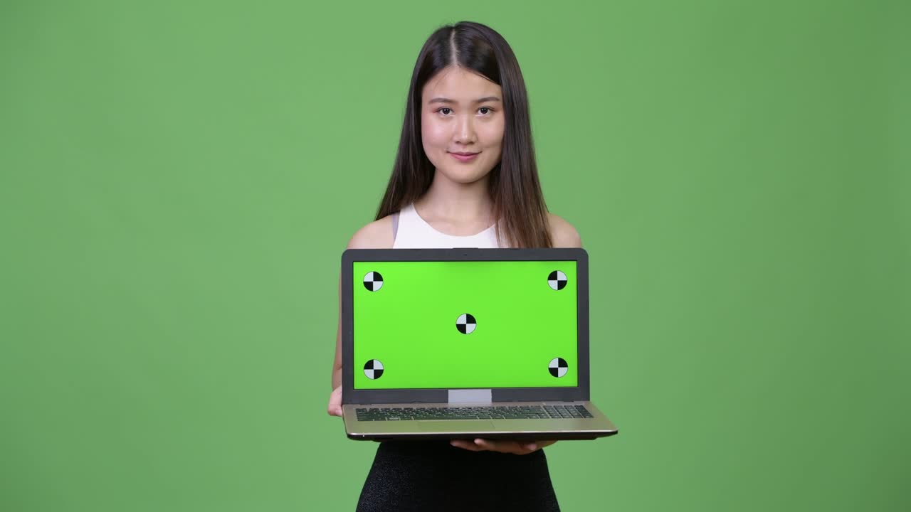 Young beautiful Asian businesswoman showing laptop
