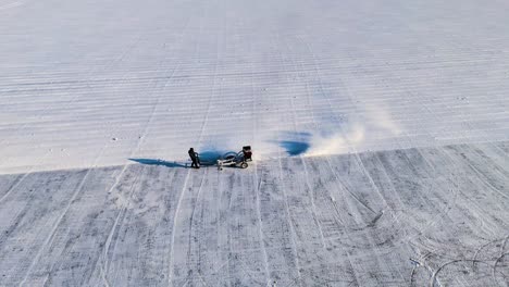 aerial shot of an ice-cutting machine working on the frozen songhua river in harbin, during the ice festival. the machine carves through the thick ice, creating a trail of snow. china