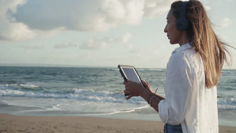 woman with tablet walking by ocean