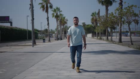 man walking on a city street by palm trees