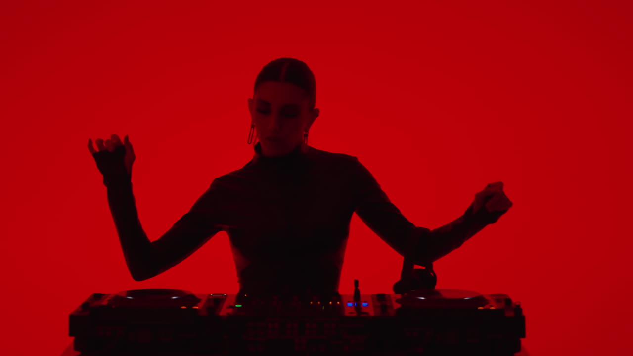 mujer dj mezclando música en el estudio de luz roja