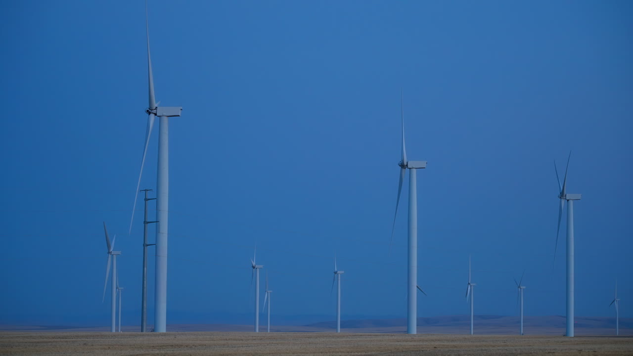 Side View Of Wind Turbines Generating Wind Energy At The Farm Against Clear Sky At Dusk. wide