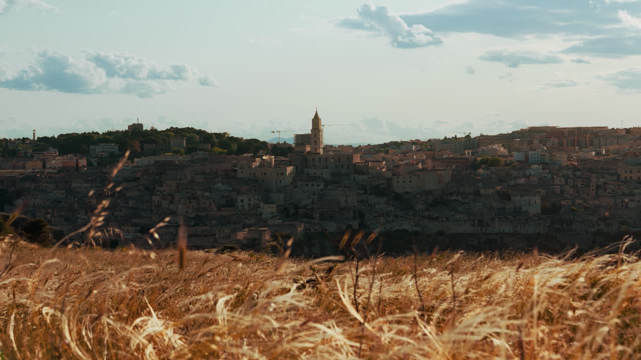 Historic Matera Sassi seen from golden fields in warm late afternoon sunlight in Basilicata, Italy