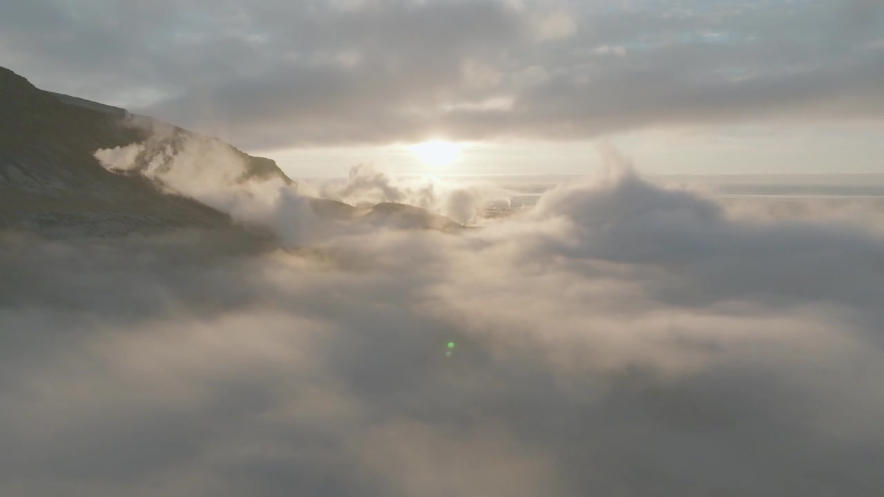 Calando in un letto di nuvole sopra le cime delle montagne nell'Islanda meridionale. Movimento di tilt verso il basso.