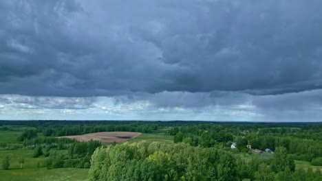 storm clouds spread high across green forest as light breaks through shining down