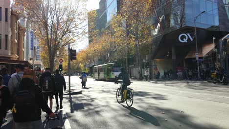 personas y ciclistas cruzando una concurrida intersección de melbourne