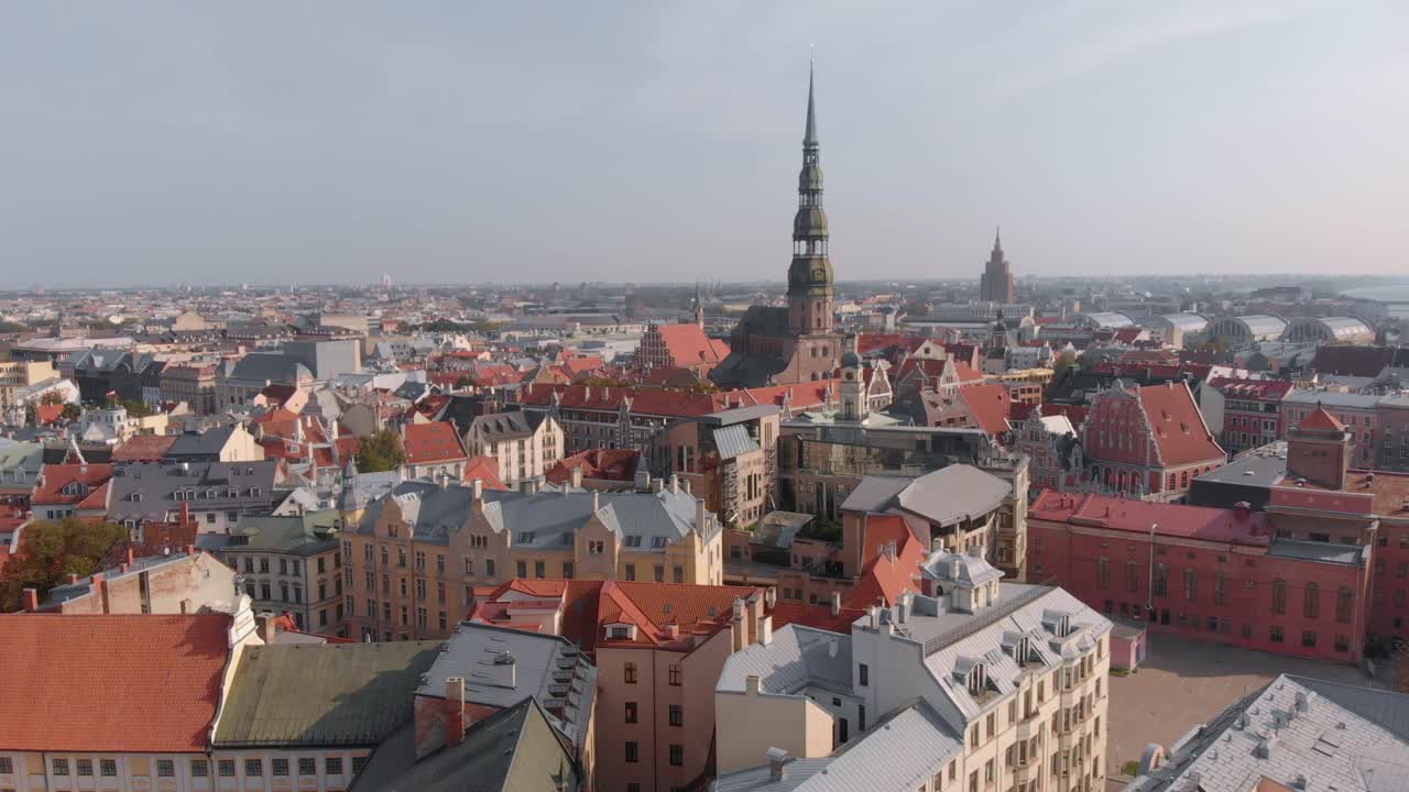 drone aéreo volando hacia la torre de la iglesia de san pedro sobre edificios en riga, letonia
