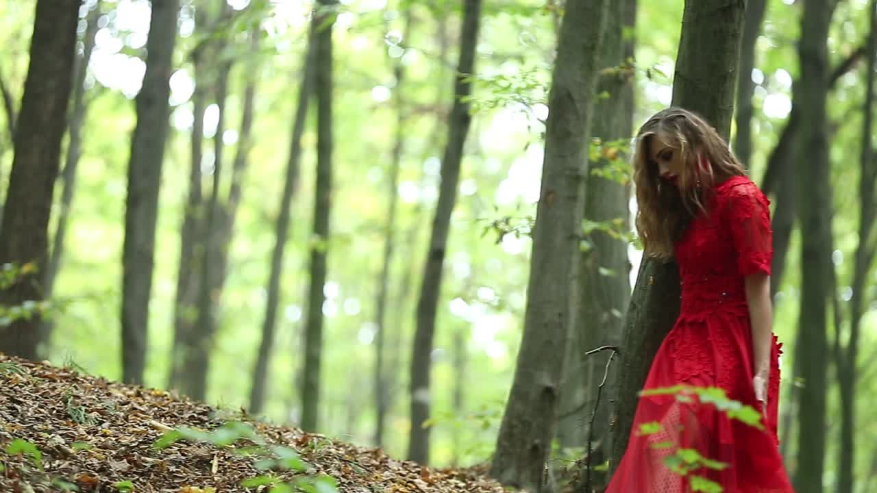 Pretty Woman Walking In The Forest. Pretty woman in a long red dress walking in the forest