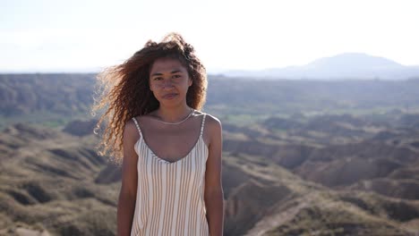 portrait of a young woman with curly hair in a vast outdoor landscape