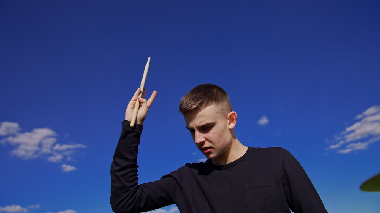 Adolescente che suona la batteria all'aperto