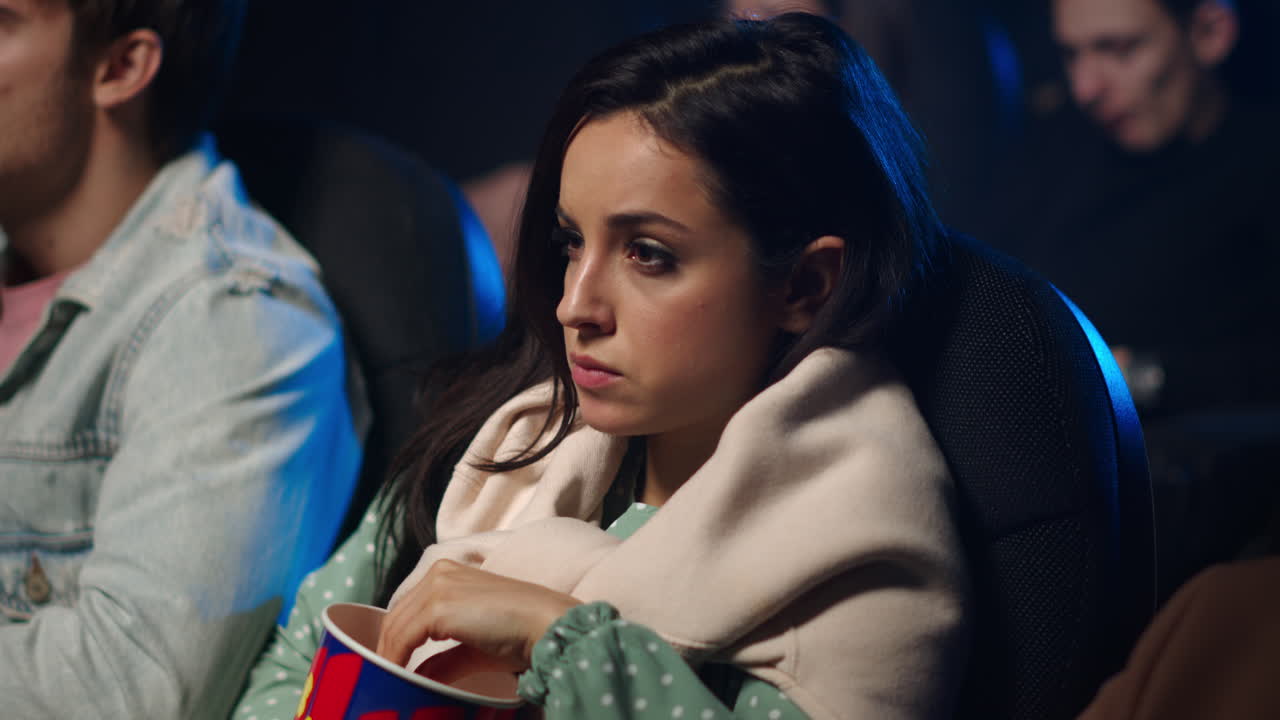 mujer asustada viendo una película en el cine