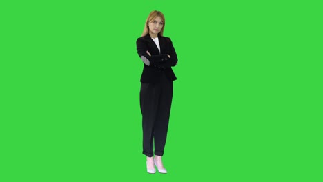 attractive middle-aged business woman posing with folded arms on a green screen, chroma key