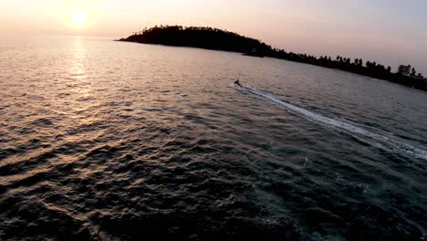 Küstenszene-Bei-Sonnenuntergang,-Nicht-Erkennbare-Leute,-Die-Jetski-Fahren