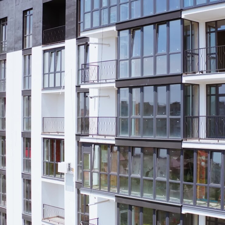 Bellissimi nuovi appartamenti residenziali. Facciata moderna di un edificio a più piani con un riflesso del paesaggio urbano nelle finestre. Edificio a più piani nei colori bianco e nero. Vista frontale.