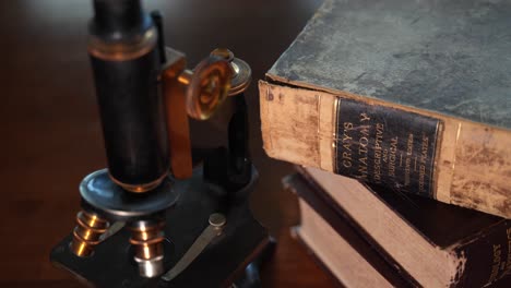 libro de referencia de anatomía antigua y un microscopio vintage en un consultorio médico o veterinario - cierre aislado