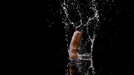 fresh ginger root fall into water with splashing droplets, isolated black background