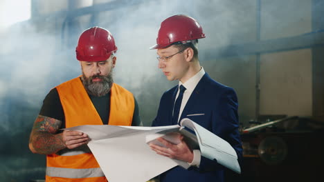 dos ingenieros estudian dibujos en el almacén