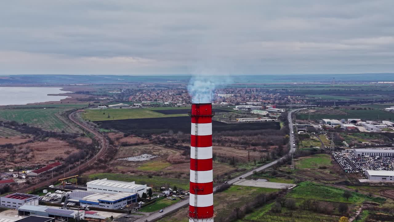Il fumo si alza da un'alta ciminiera in una zona industriale vicino all'acqua