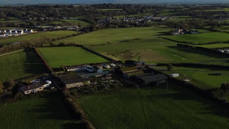 establishing aerial view over patchwork anglesey farm to reveal snowdonia mountain range on the horizon