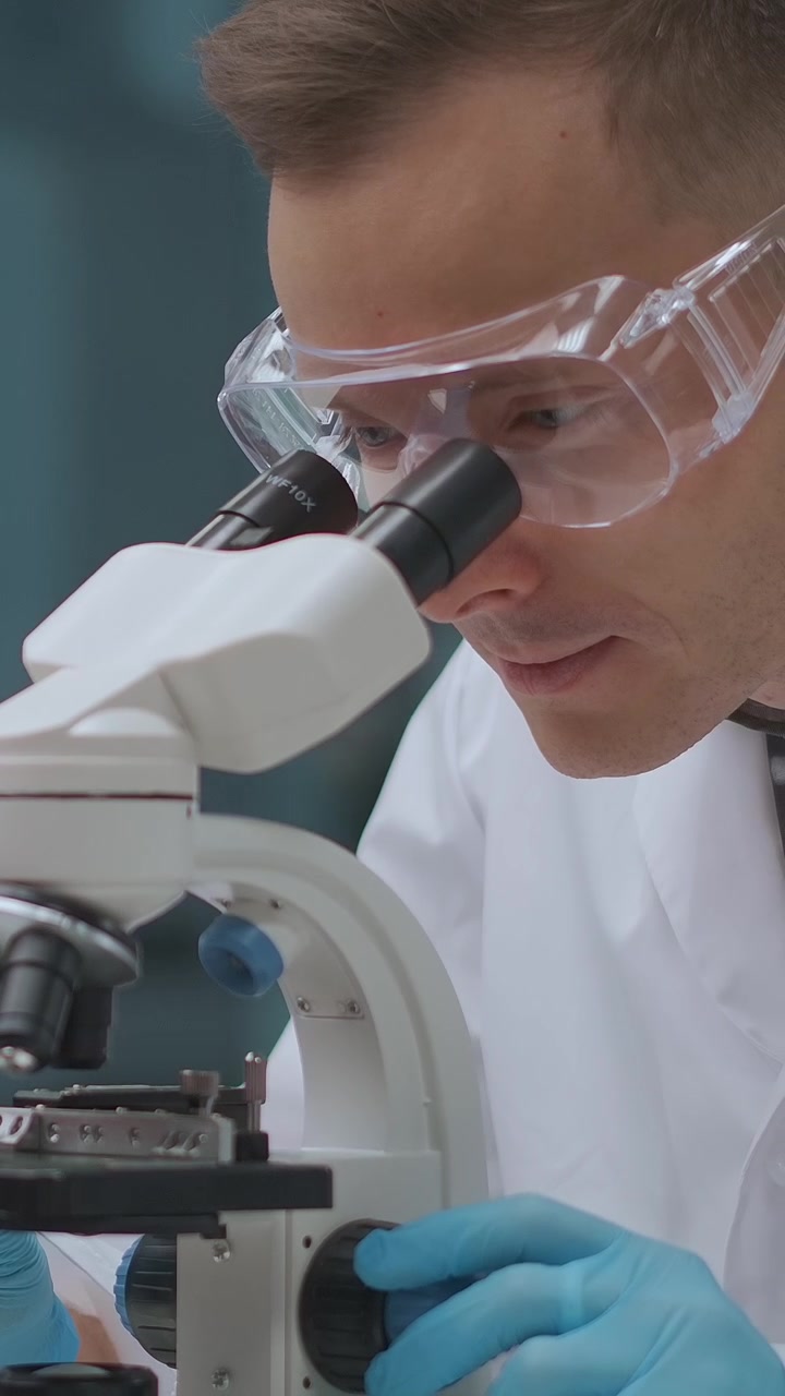 Focused Scientist Using Microscope for Research in Laboratory