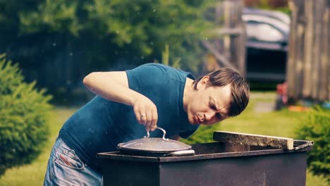 close-up slow motion man cooks pilaf in cauldron on coals on a grill blows the coals