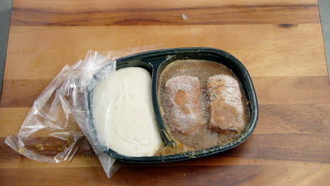 tampered food meal frozen box being dropped on a wooden dining table with force