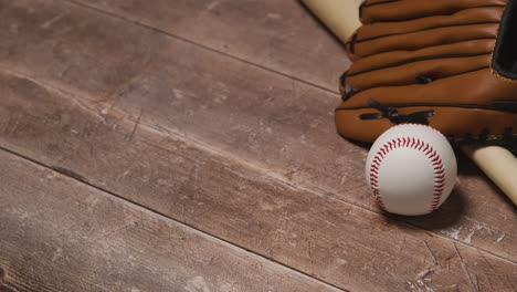 close up studio baseball still life with wooden bat and ball in catchers mitt on wooden floor 5