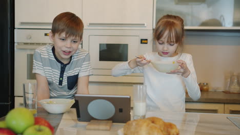 children eating breakfast and watching tablet