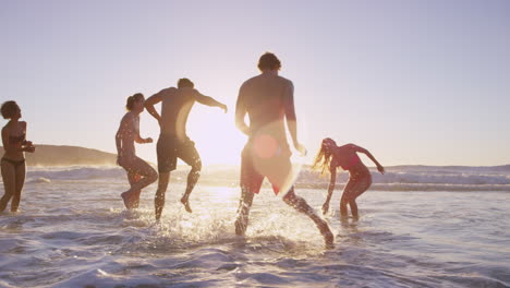 Eine-Vielfältige-Gruppe-Von-Freunden-Schwimmt-Bei-Sonnenuntergang-Im-Meer