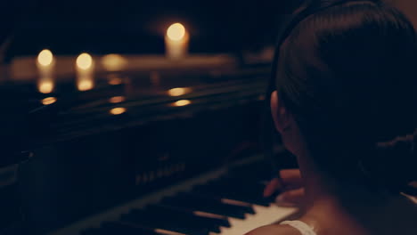 woman playing piano in a living room at night