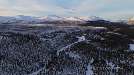 breathtaking panoramic aerial footage near fish lake in whitehorse, yukon, showcasing the expansive snowy landscape and surrounding mountains in wintertime.