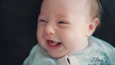 a newborn baby, smiling and crawling, lies on a dark background