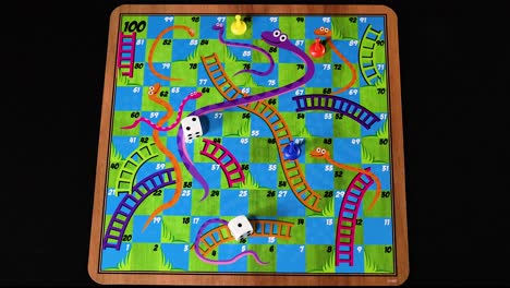 hands rolling dice on snakes and ladders board