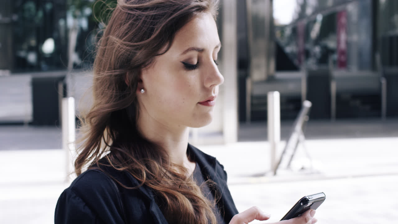 Attraktive Geschäftsfrau als Pendlerin nutzt Smartphone in der Londoner City.