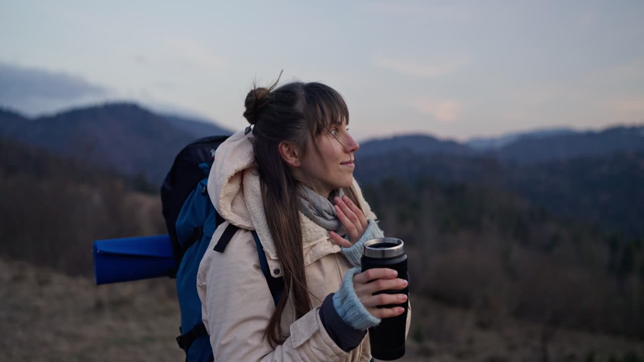 Woman hiker enjoying mountain view with thermos