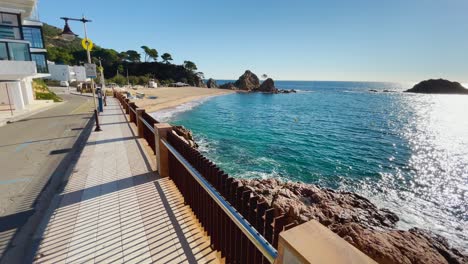 tossa de mar bay seen from the castle to the beach with coarse sand and turquoise blue sea water old walled medieval village fishing village mediterranean sea walking along the promenade