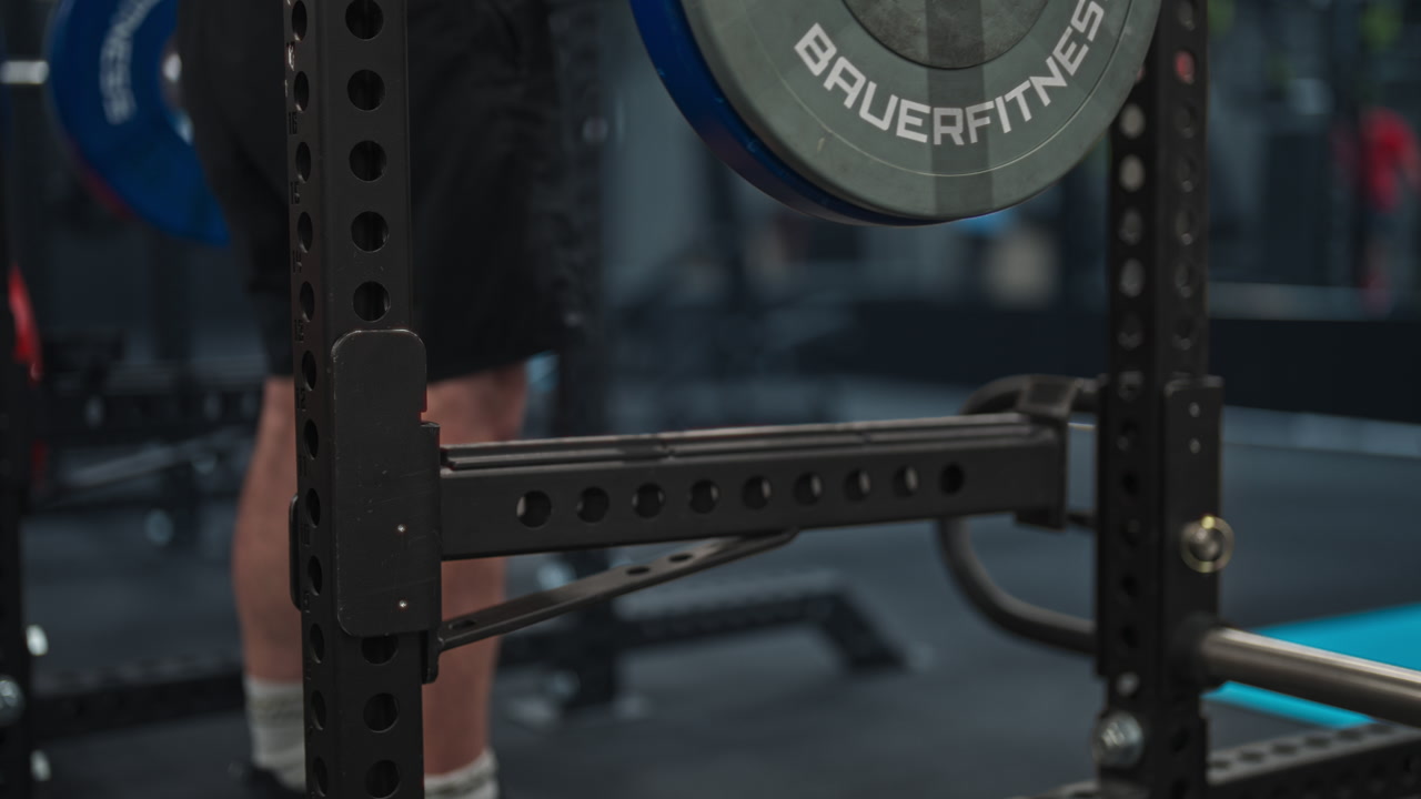 Man At The Gym Lifting A Barbell Loaded With A Bumper Plate. closeup shot