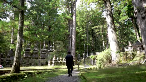 male tourist walking over gobblestone pathway in the okunion forest cemetary in japan