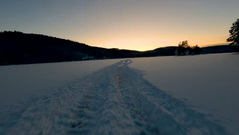 Snow-covered-tracks-are-leading-through-a-serene,-snowy-landscape-at-dawn