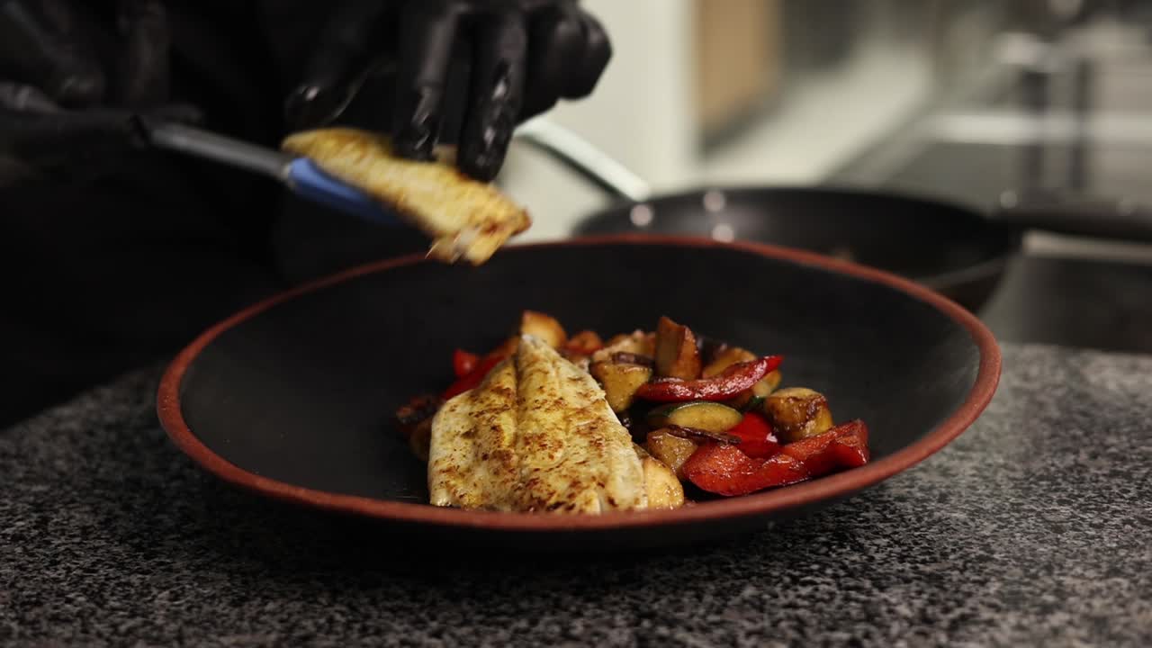 chef che prepara pesce alla griglia con verdure arrostite