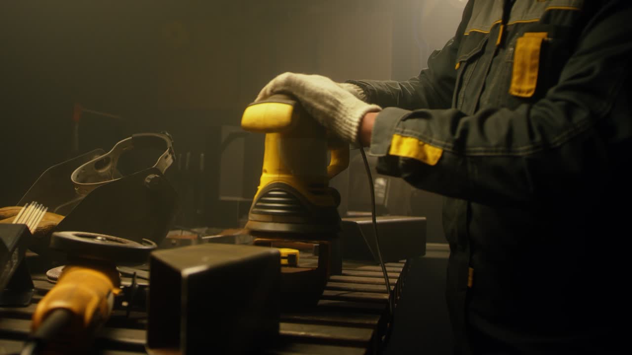 рабочий полирует металл с помощью шлифователя. интерьер завода тяжелой промышленности с рабочим, использующим шлифователь. электрическое шлифование стальных труб на заводе. медленное движение. крупный план. 4k видео. снято на красном