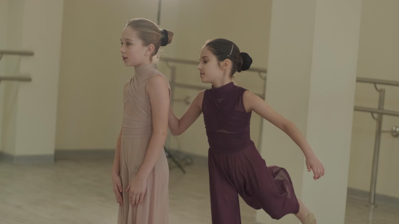 un grupo de jóvenes estudiantes de ballet con ropa de baile negra practicando posiciones en un amplio estudio de ballet con pisos de madera y barras montadas en la pared. expresiones enfocadas y movimientos sincronizados.