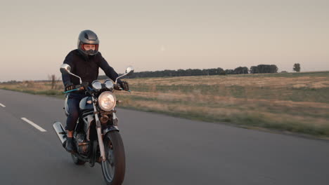 um motociclista anda de moto antes do pôr do sol