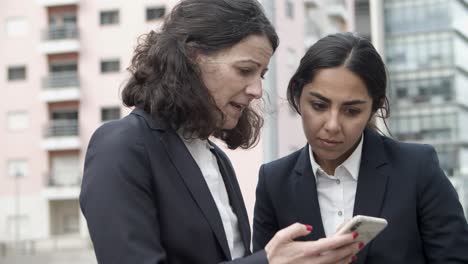 mujeres de negocios concentradas usando teléfonos inteligentes en la calle