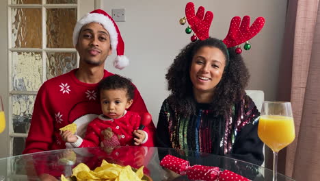 young parents with small child joining christmas video call waving and talking to camera