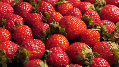 una gran cantidad de fresas rojas y maduras girando, en primer plano