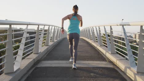 mujer joven corriendo por un puente