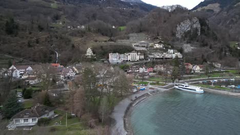 Orbit-ascend-aerial-above-pier-and-small-dock-on-shoreline-of-Lake-Walen-with-hotels