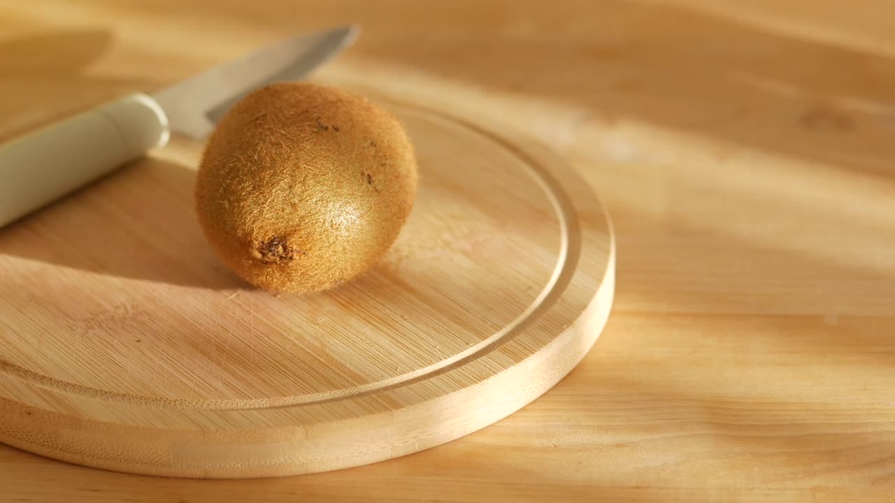 Kiwi op een houten snijplank met een mes
